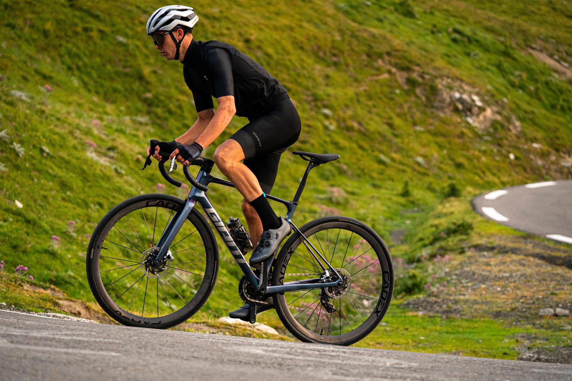 a man riding a bike on a road with a mountain in the background