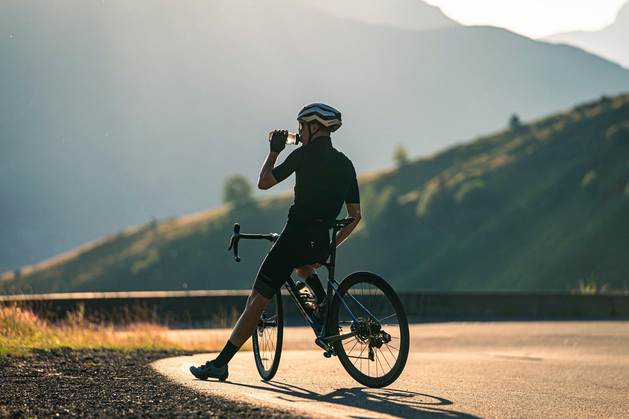 a man riding a bike on a road with a mountain in the background