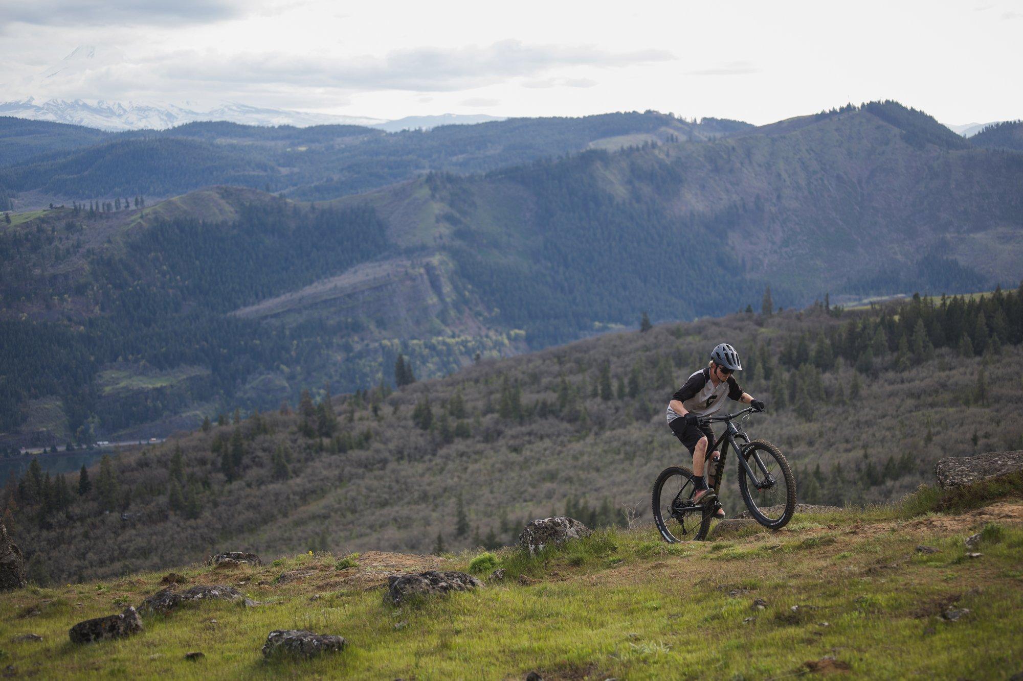 a person riding a mountain bike on a grassy hill