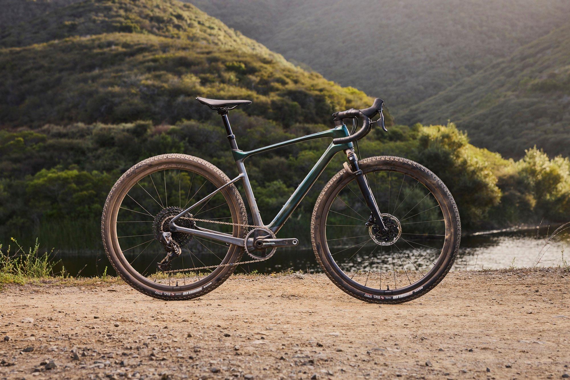 a gravel bike is parked on a dirt road near a lake