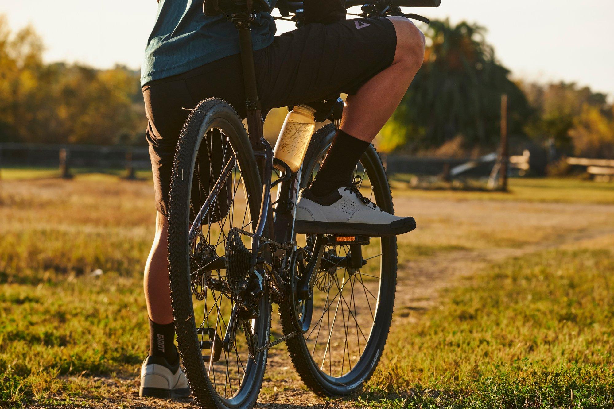 a man riding a bike on a dirt road in a field