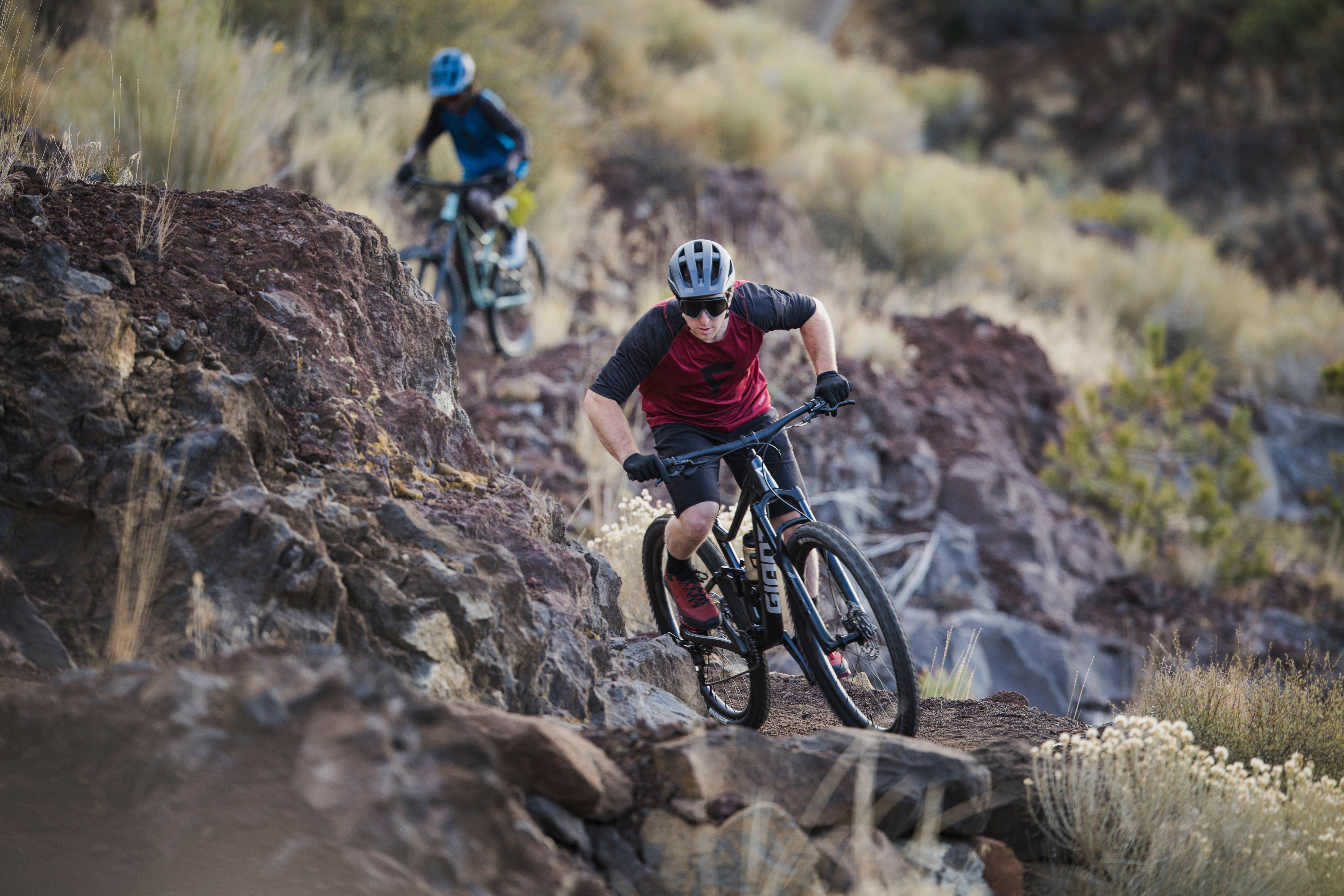 two mountain bikers riding down a rocky trail in the mountains