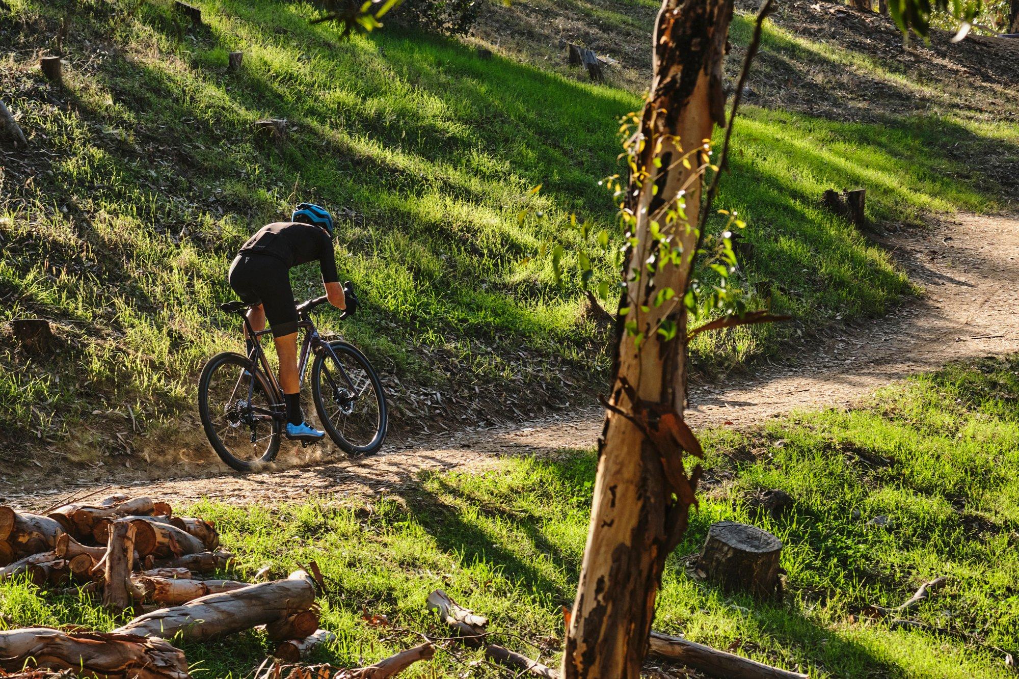 a man riding a bike on a trail next to a tree