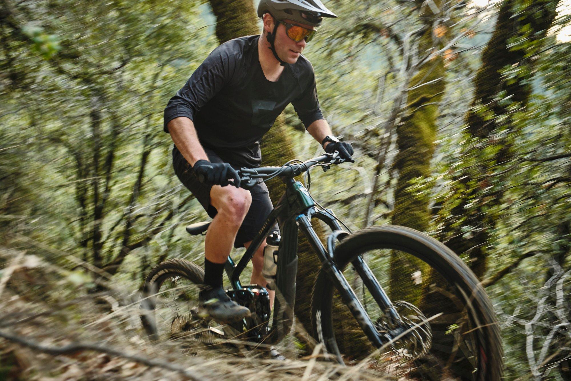 a man riding a mountain bike on a trail in the woods