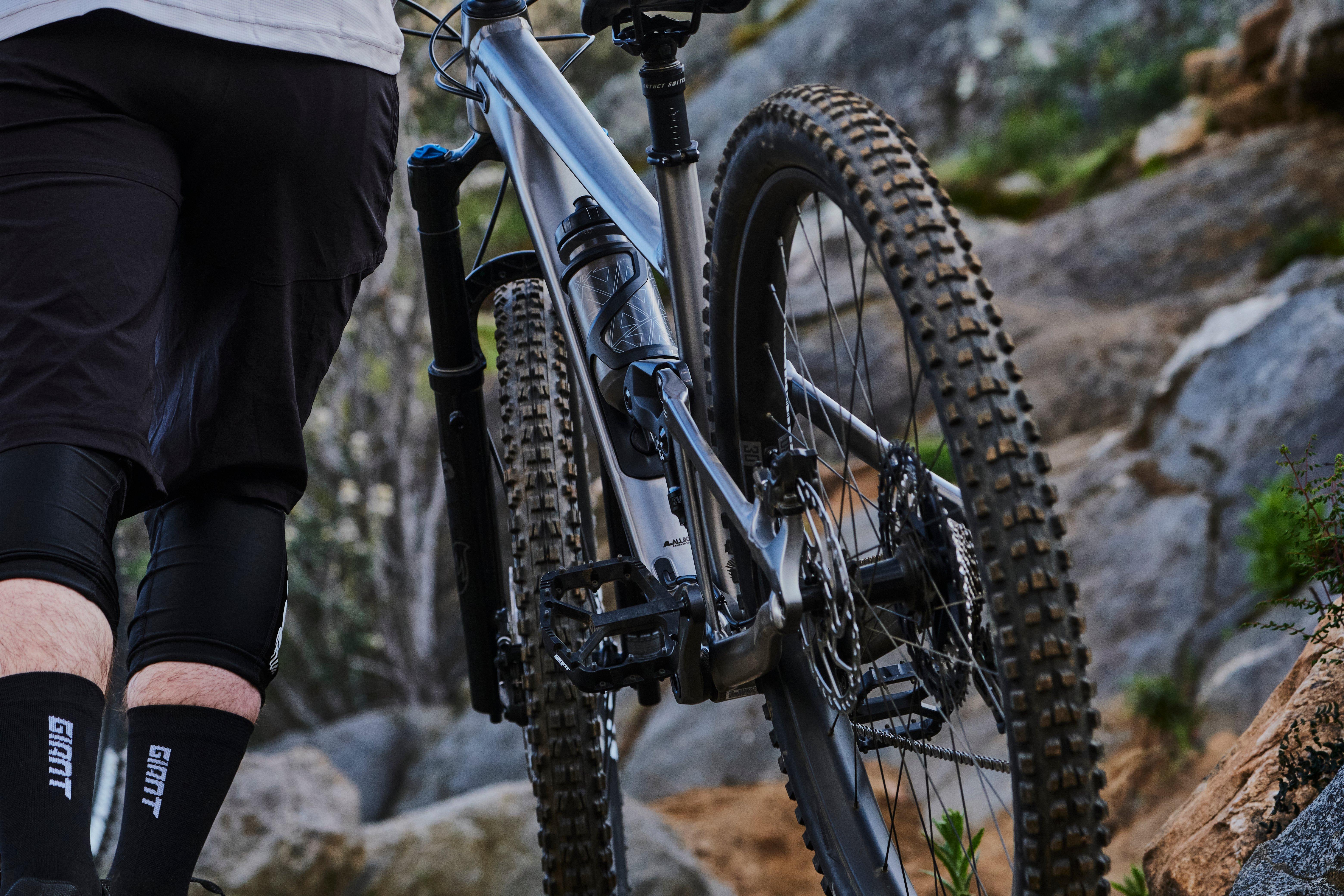 a man walking with a bike on a rocky trail
