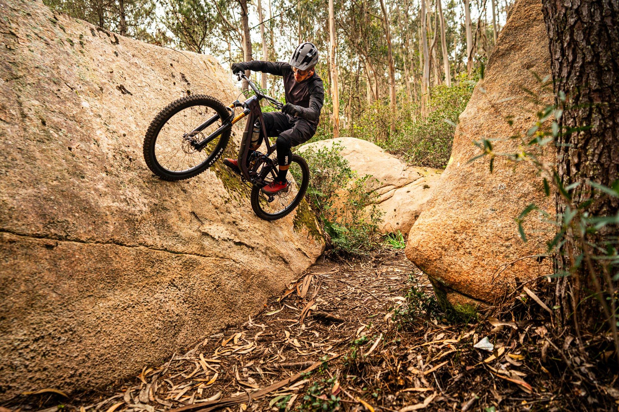 a mountain biker riding a bike on a rock in the woods