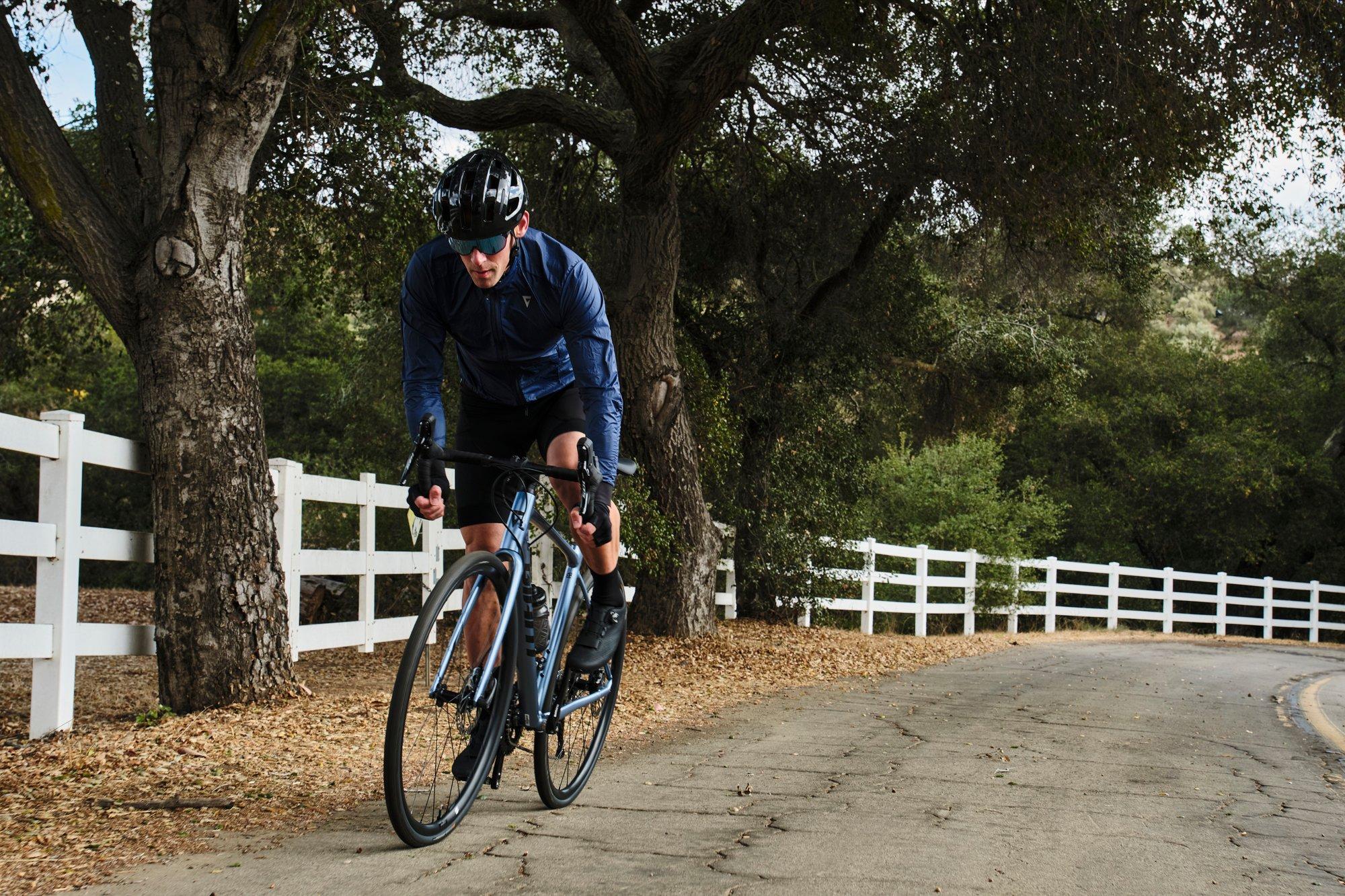 a man riding a bike down a road next to a white fence