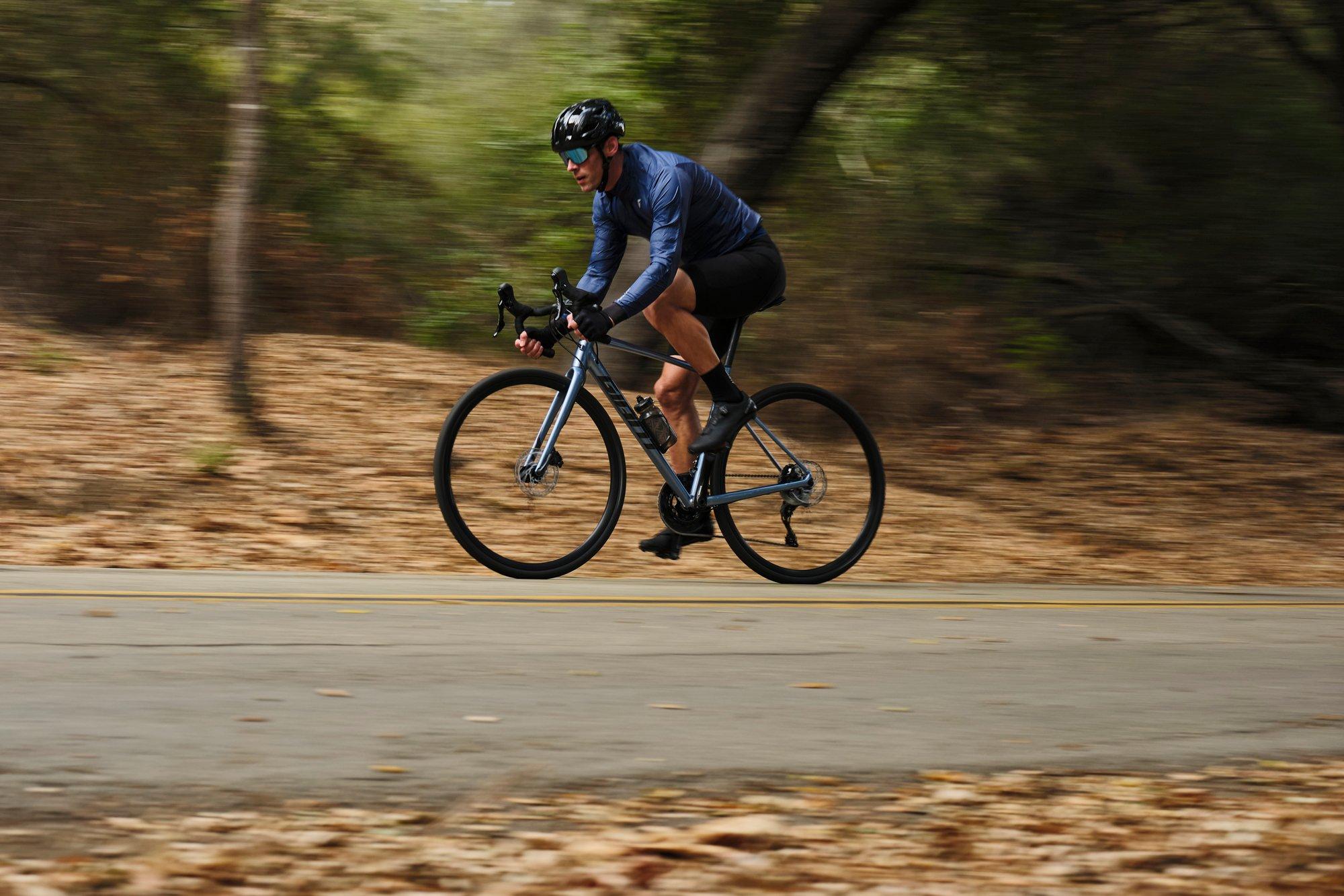 a man riding a bike down a road in the woods