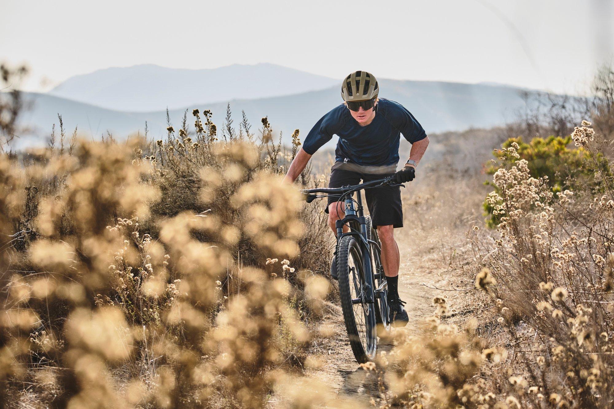 a man riding a mountain bike through a field of tall grass