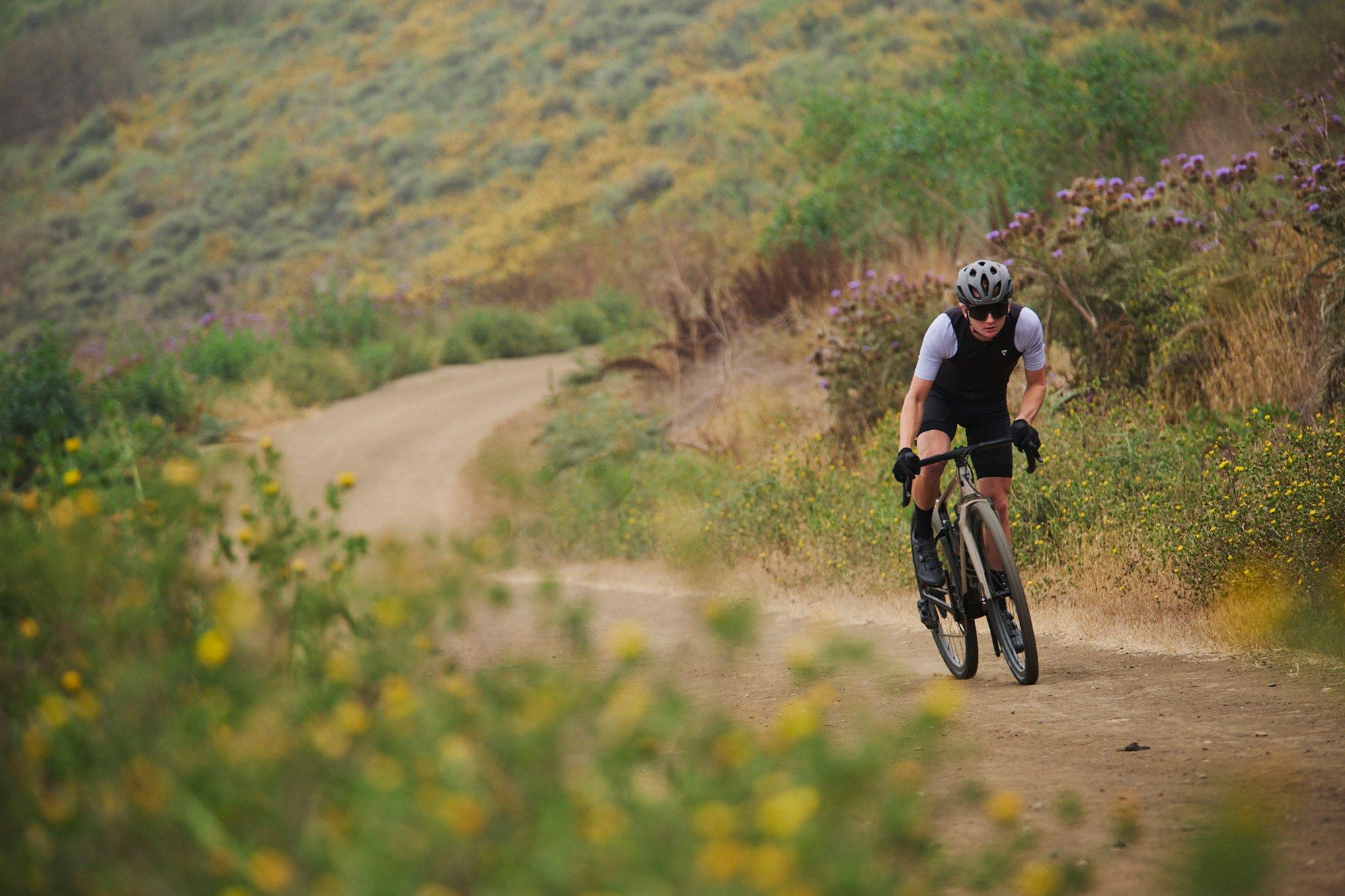a man riding a bike on a dirt road near a field