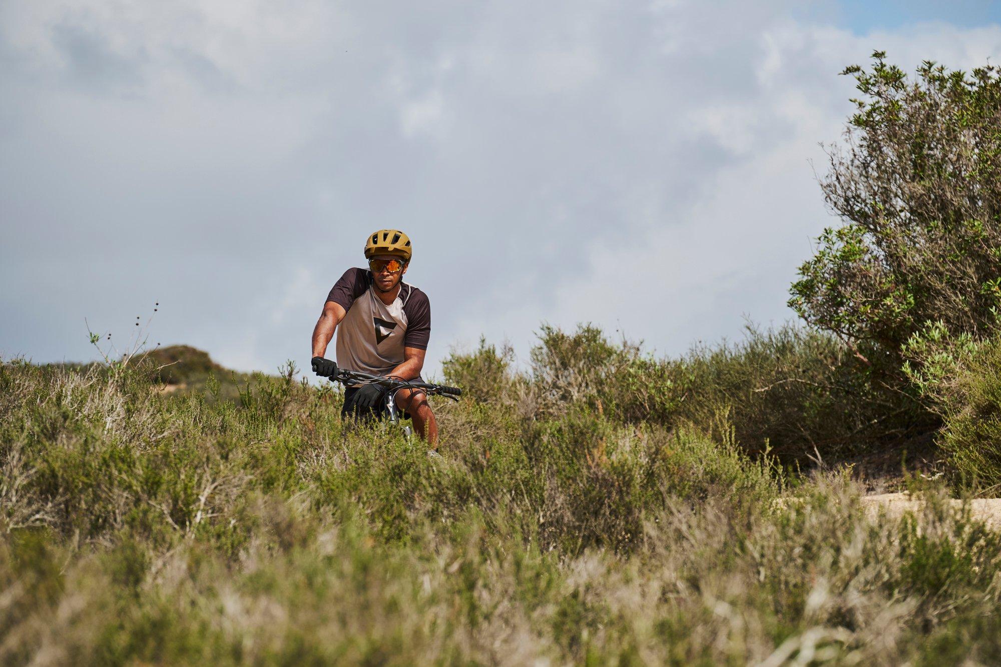 a man riding a mountain bike through a field of tall grass