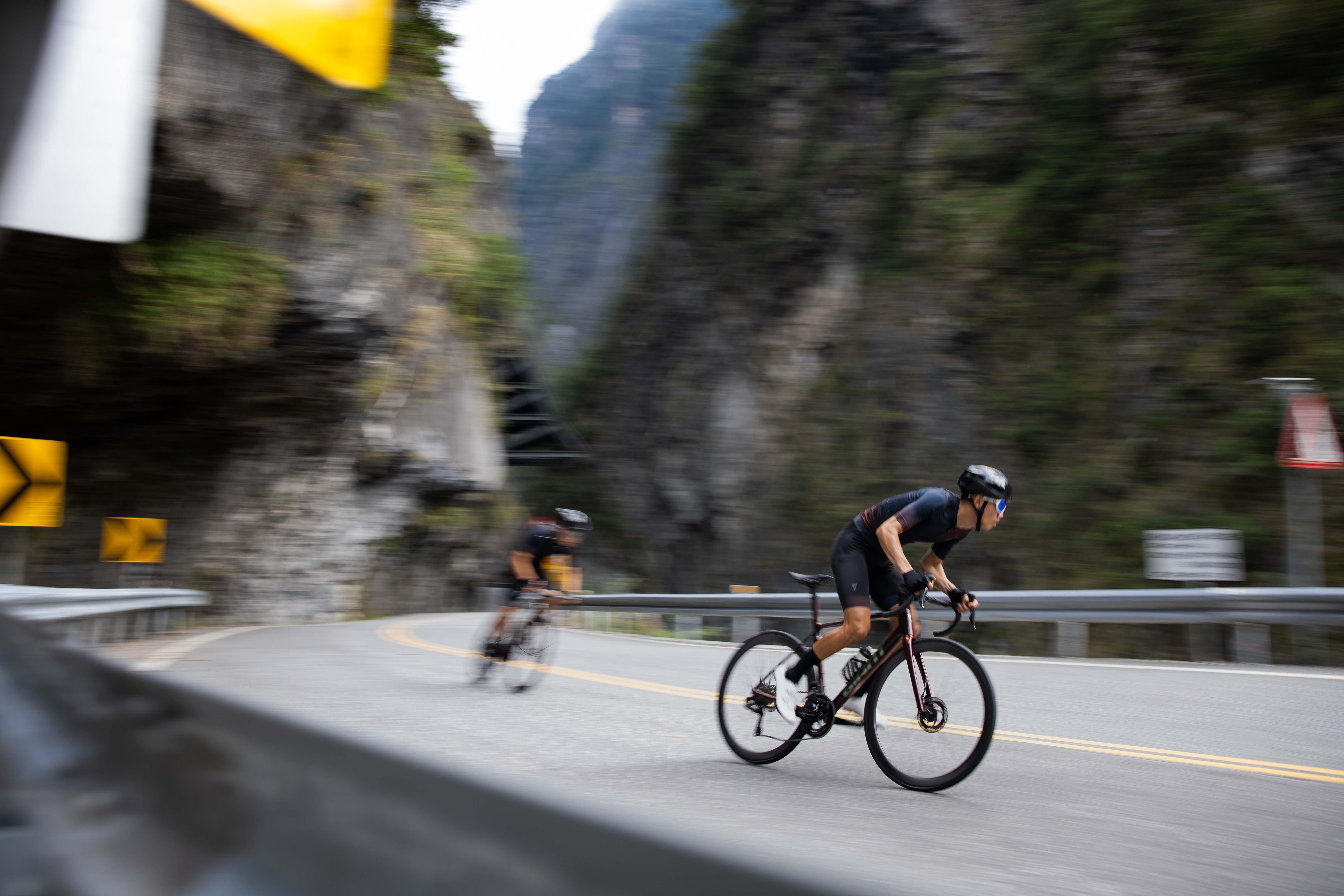 two men riding bicycles down a mountain road in the mountains
