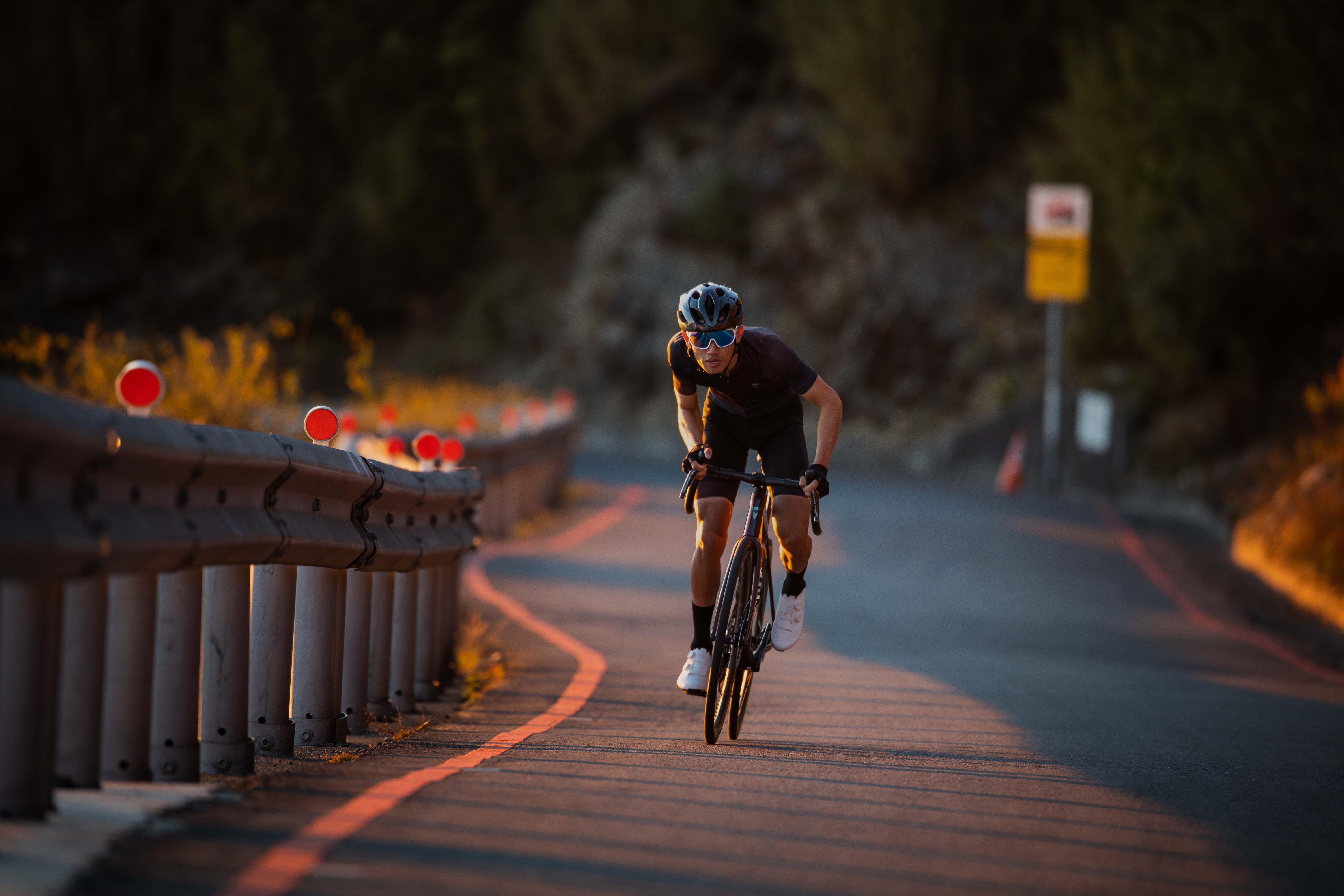 a cyclist riding down a road with a guard rail on the side