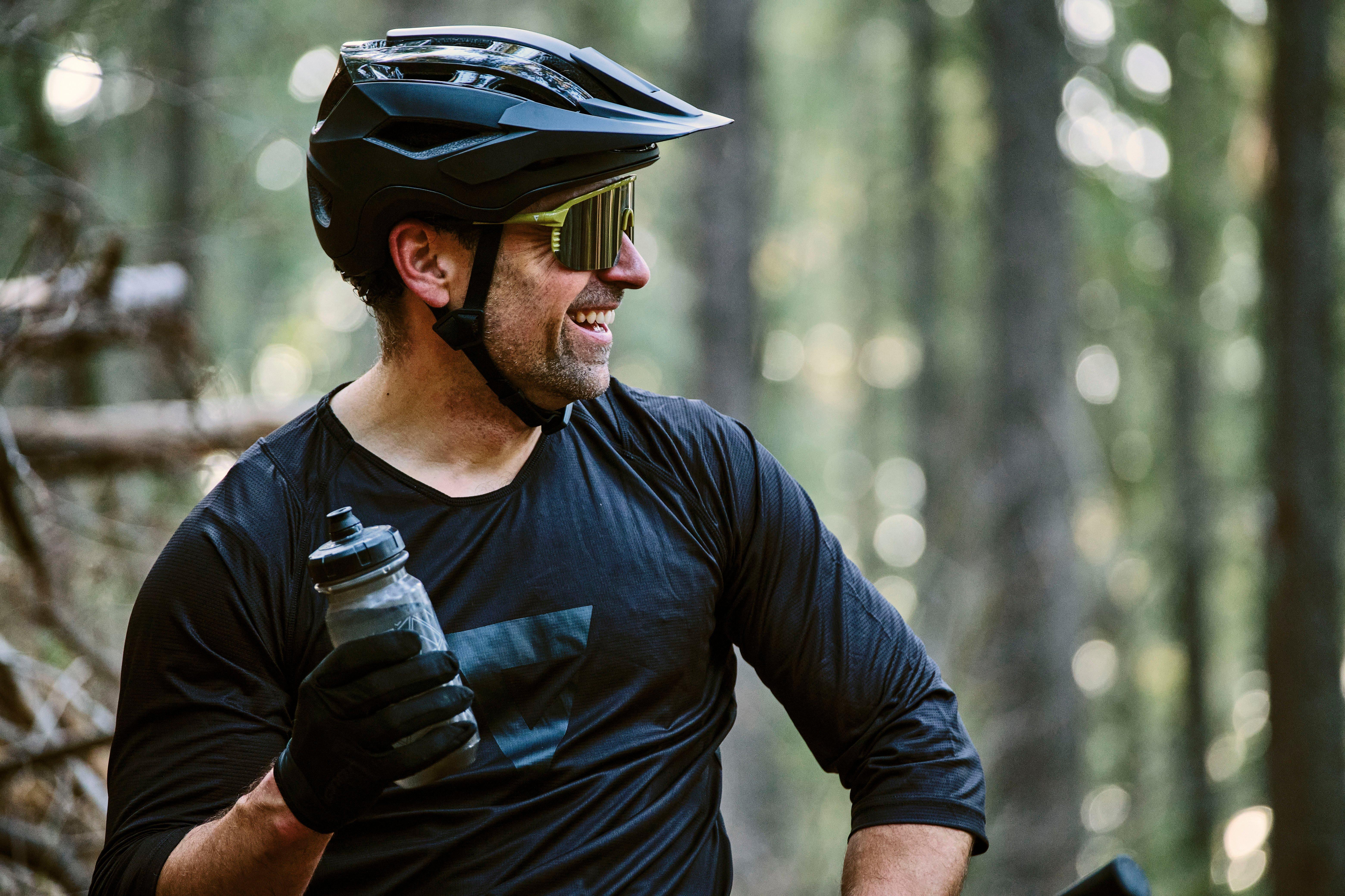 a man in a helmet and black shirt holding a water bottle