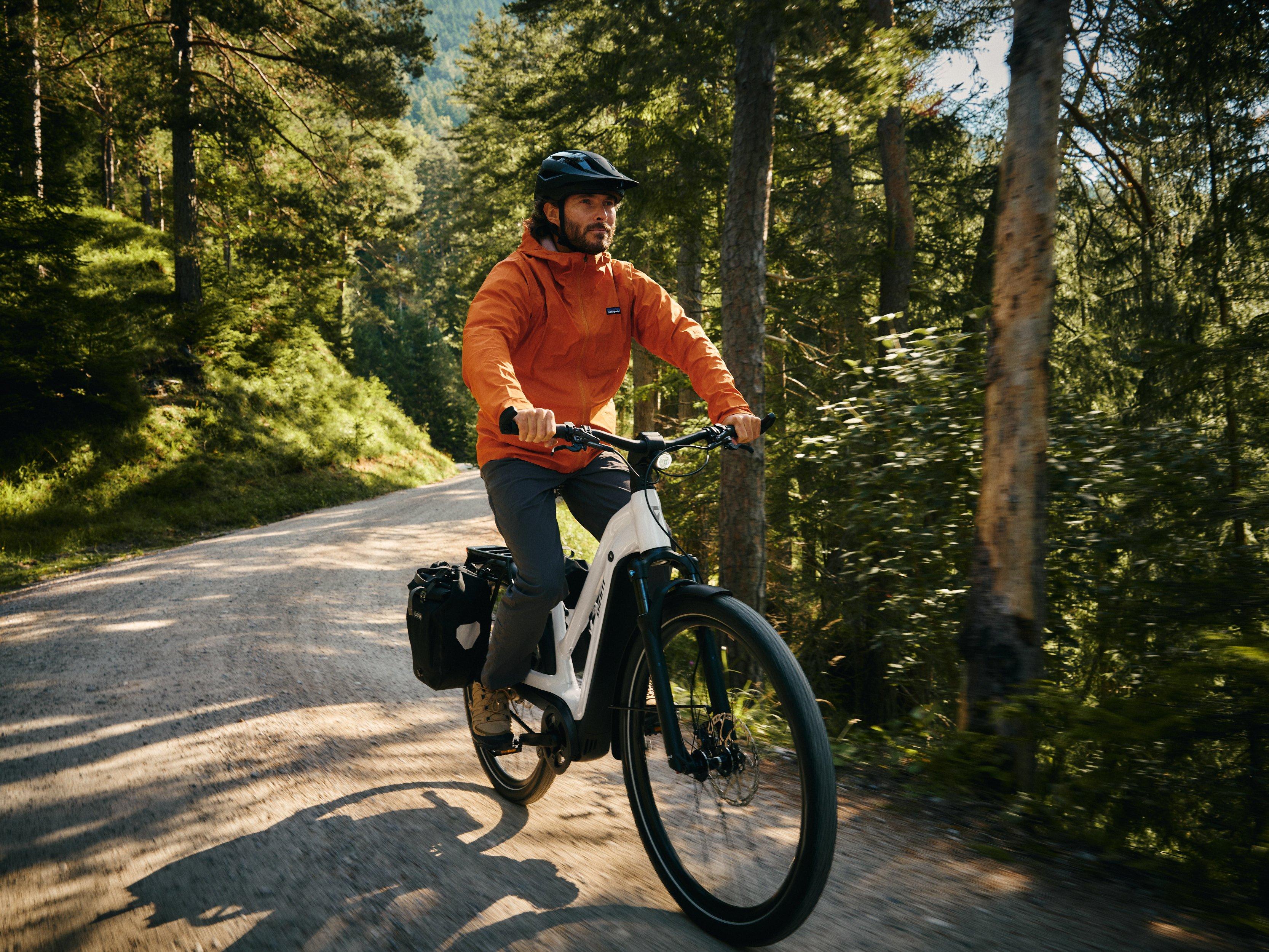 a man riding a bike on a grassy field with mountains in the background