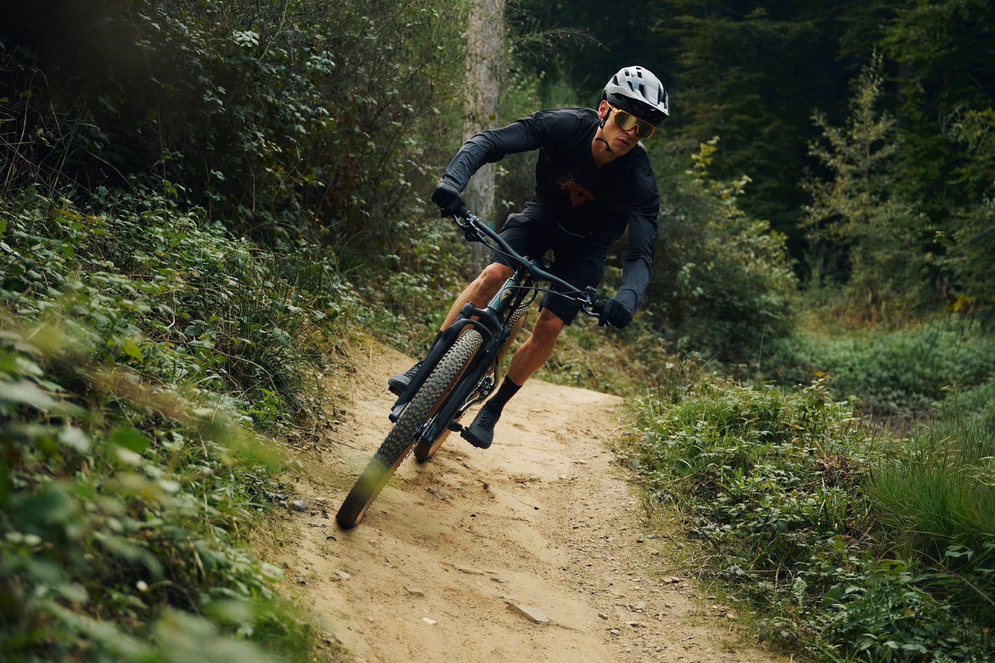 mountain biker riding down trail in the forest