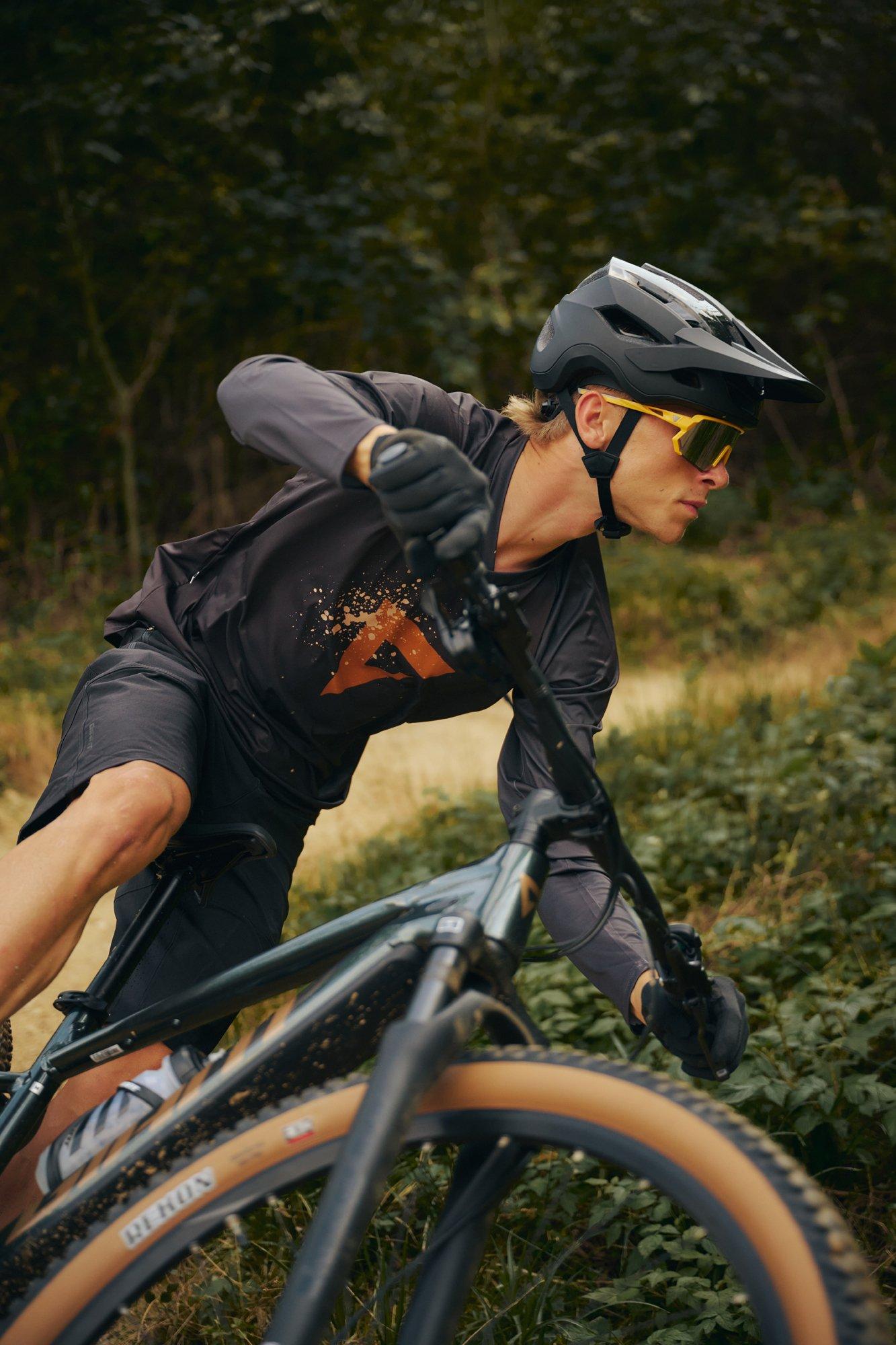 a man riding a bike down a dirt path in the woods