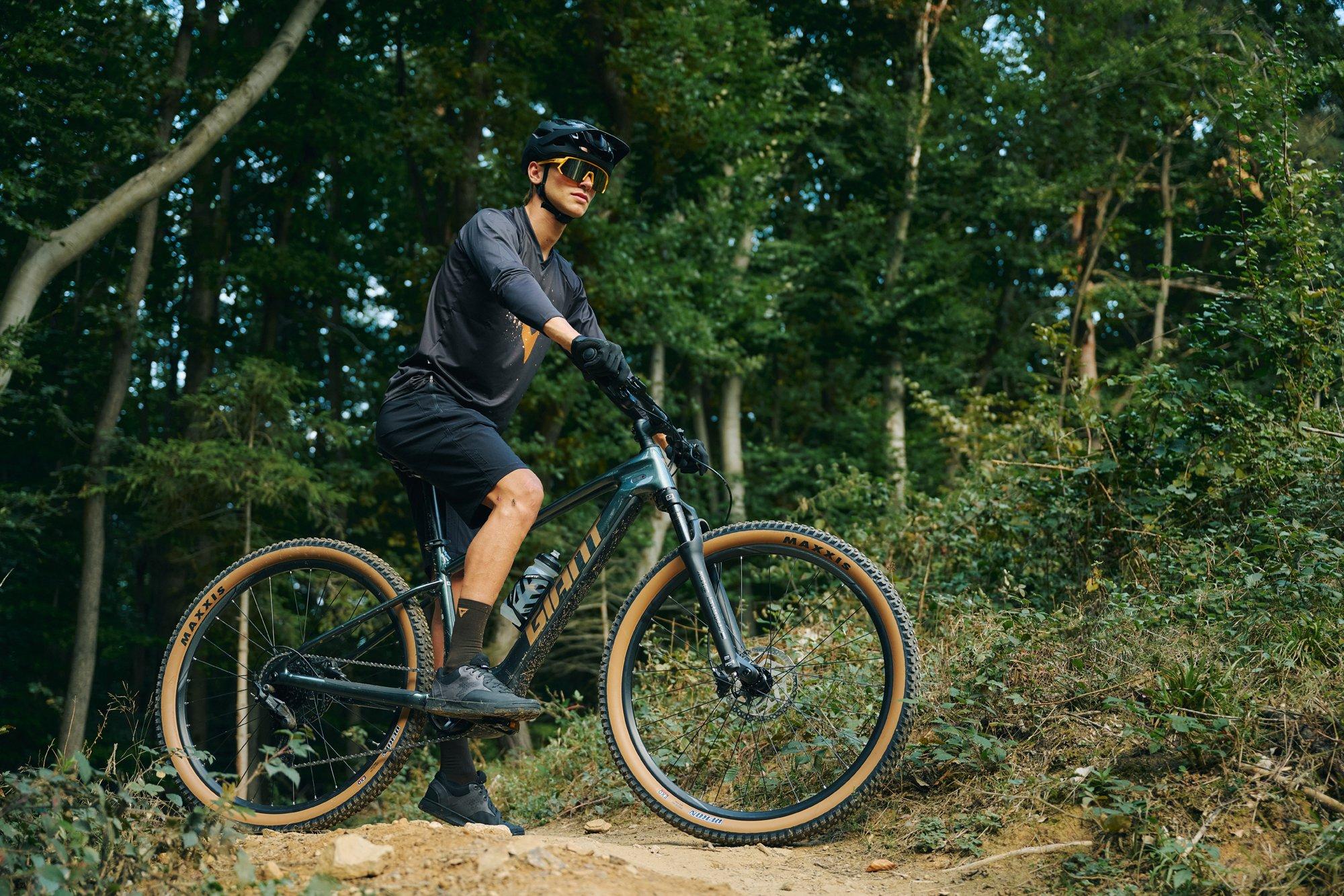 mountain biker standing on his bike on a trail in the forest