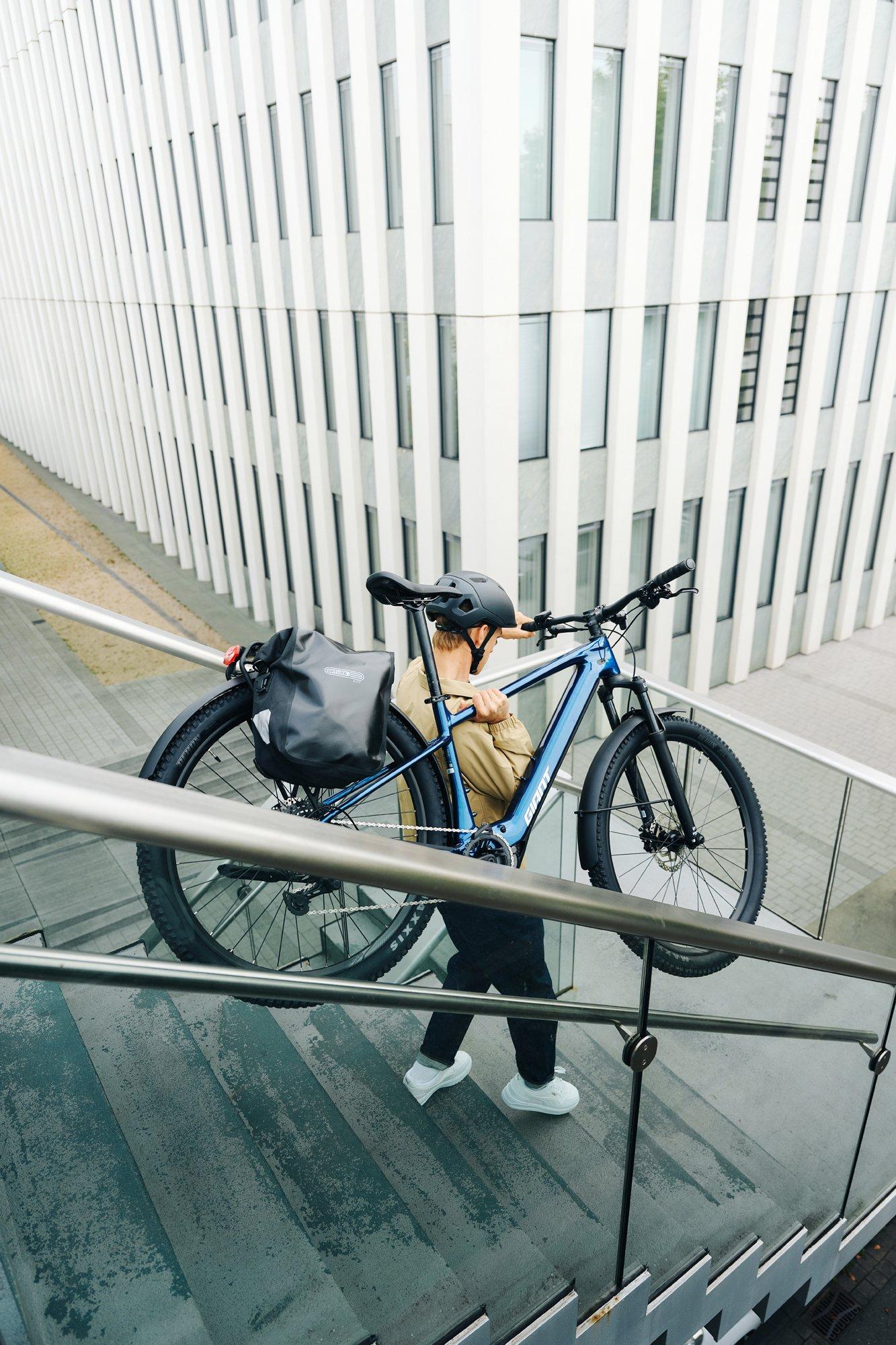a man carrying a bike down a flight of stairs