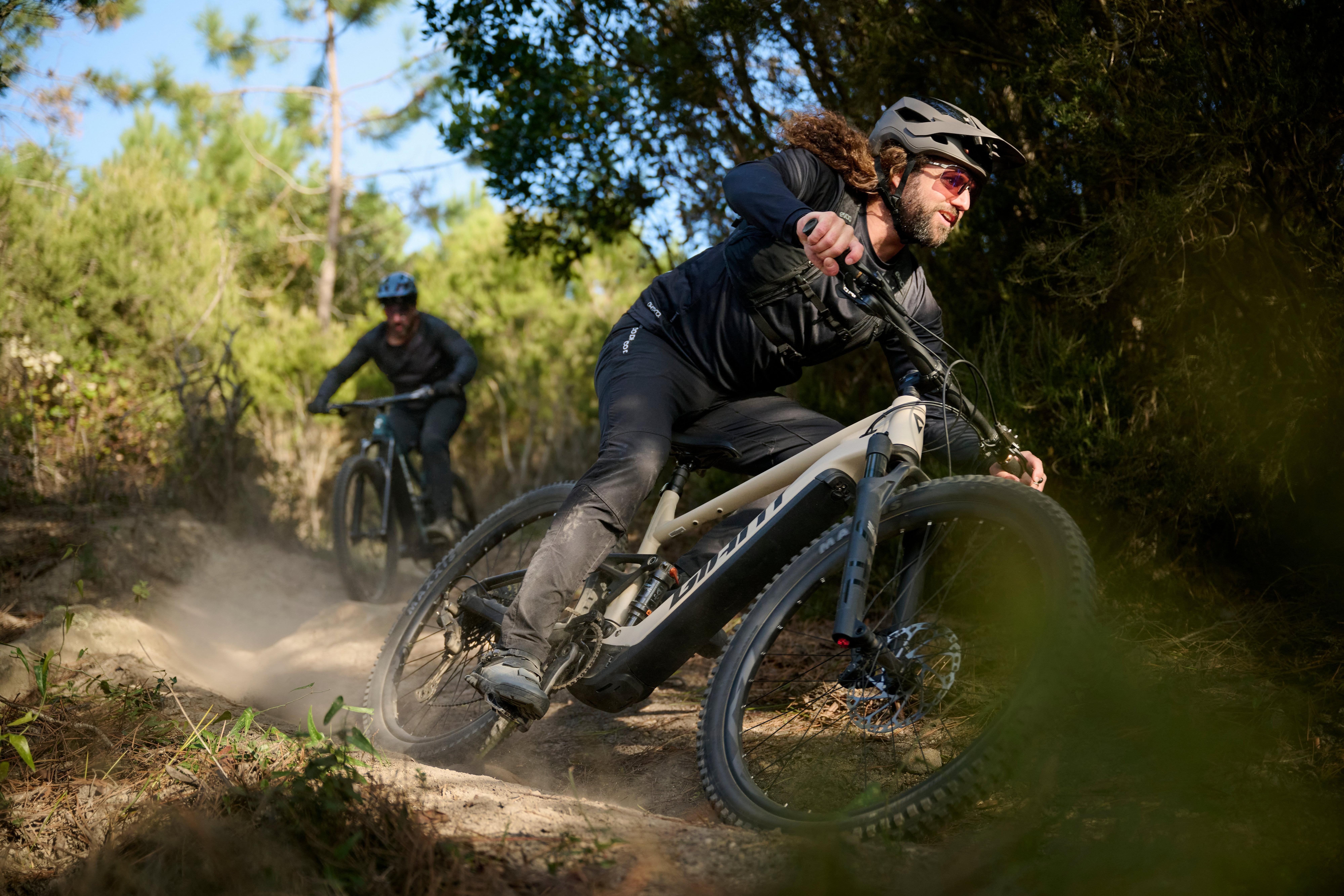 Two mountain bikers riding Giant E-bikes on a rugged dirt trail.