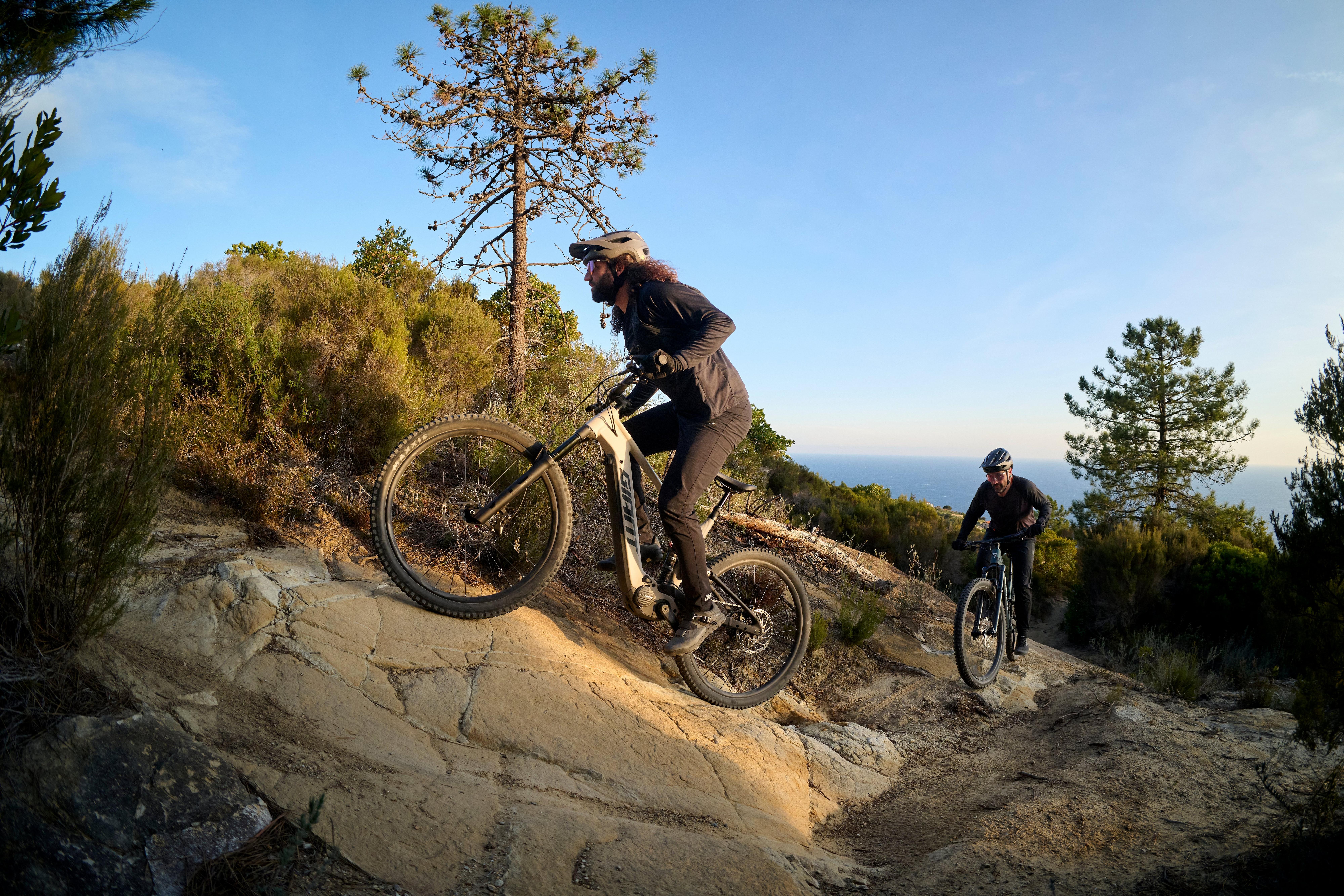 Riders on Giant electric mountain bikes tackling a dirt trail.