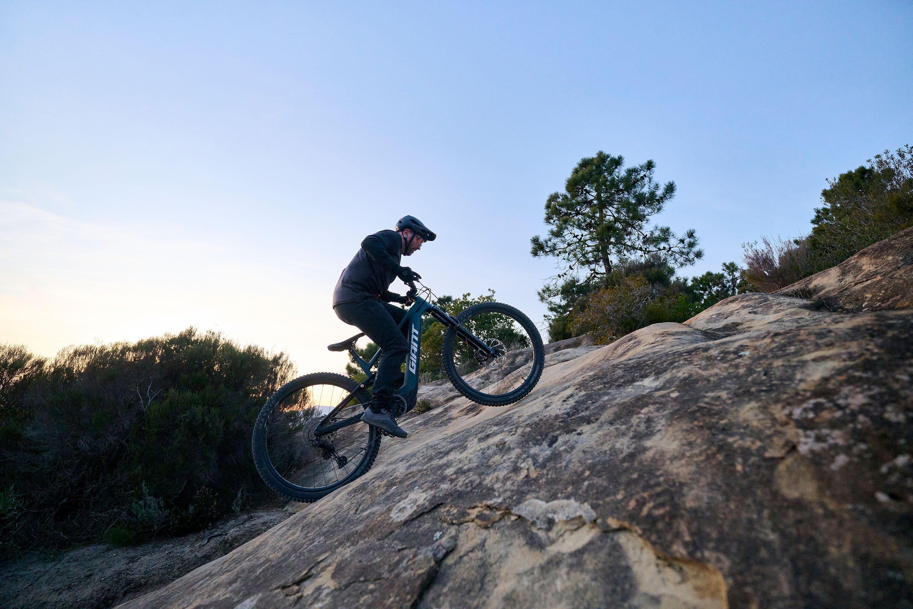 a man riding an electric mountain bike on a rocky hill