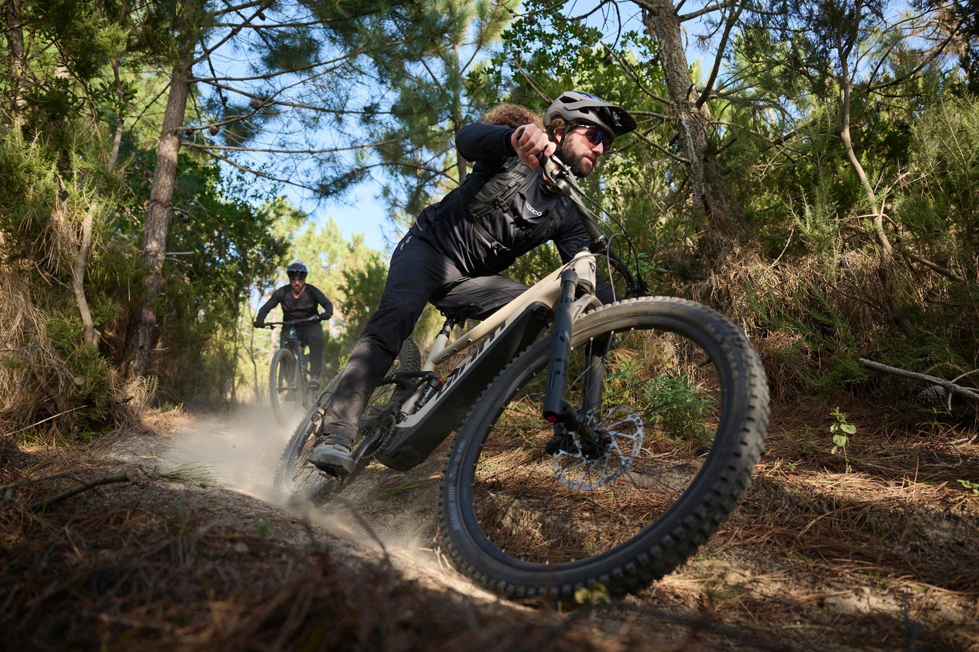 men riding an electric mountain bike on a trail in the woods