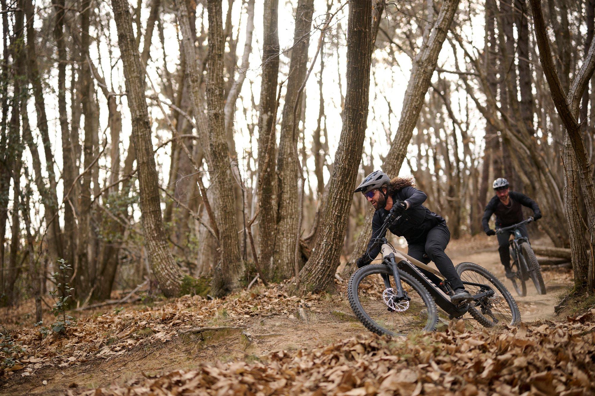 a couple of people riding mountain bikes through a wooded area