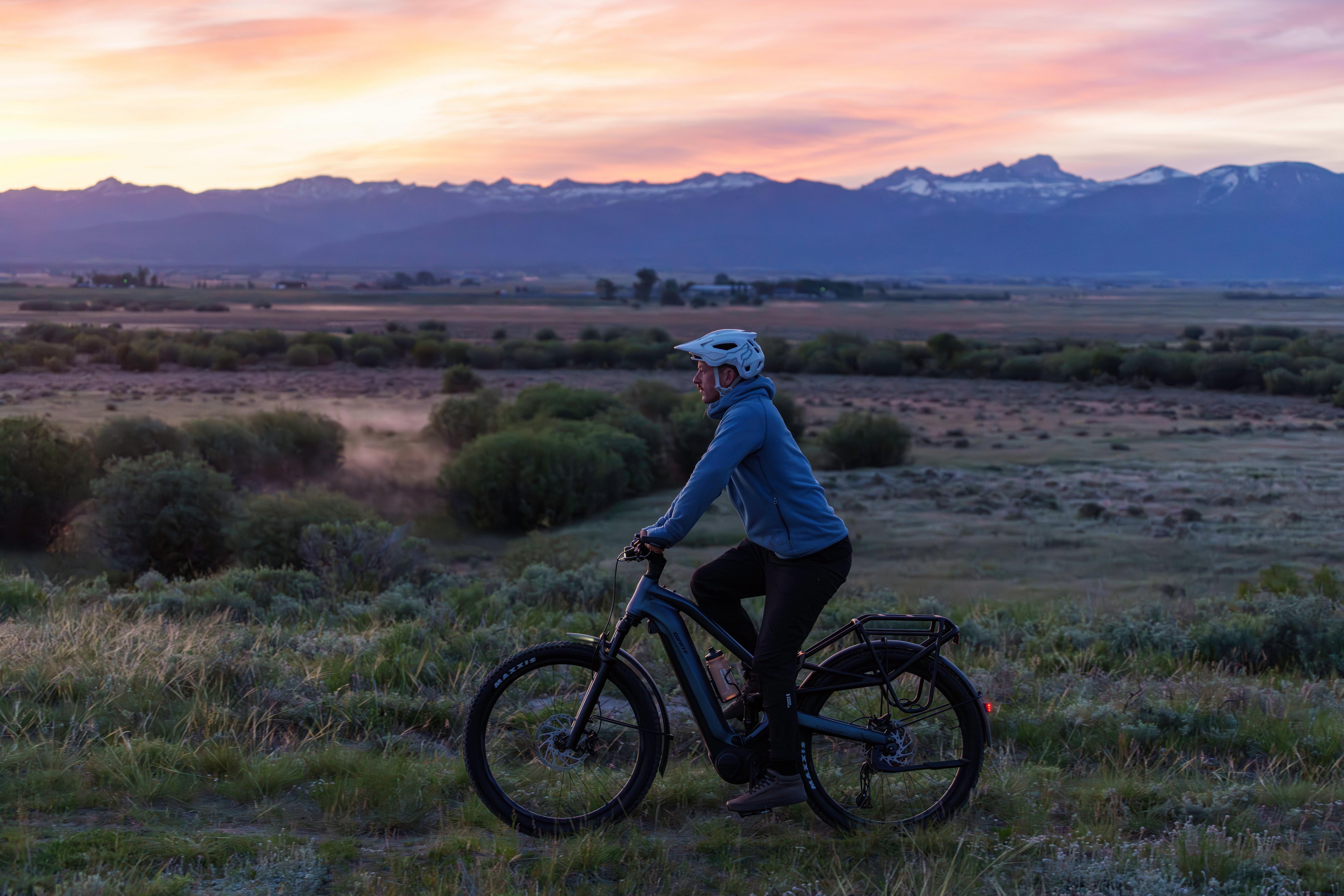 a person riding a bike in a field with a sunset in the background