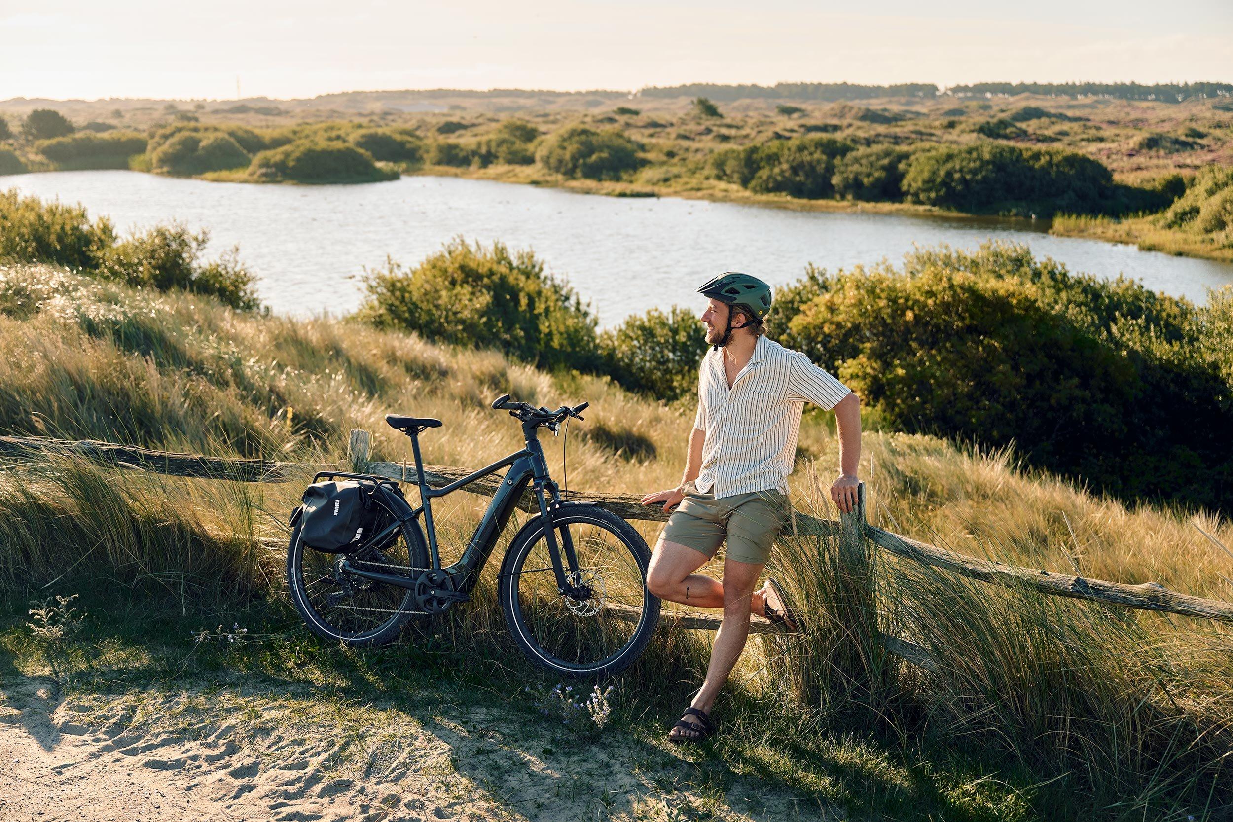 a man leaning against a fence with a bike next to him