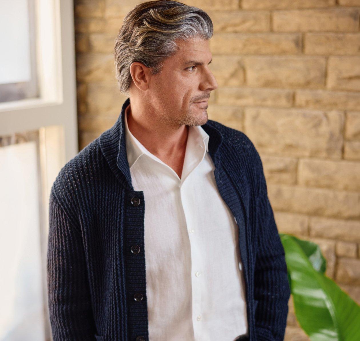 A man wearing a beige overshirt with dark brown tie and white shirt