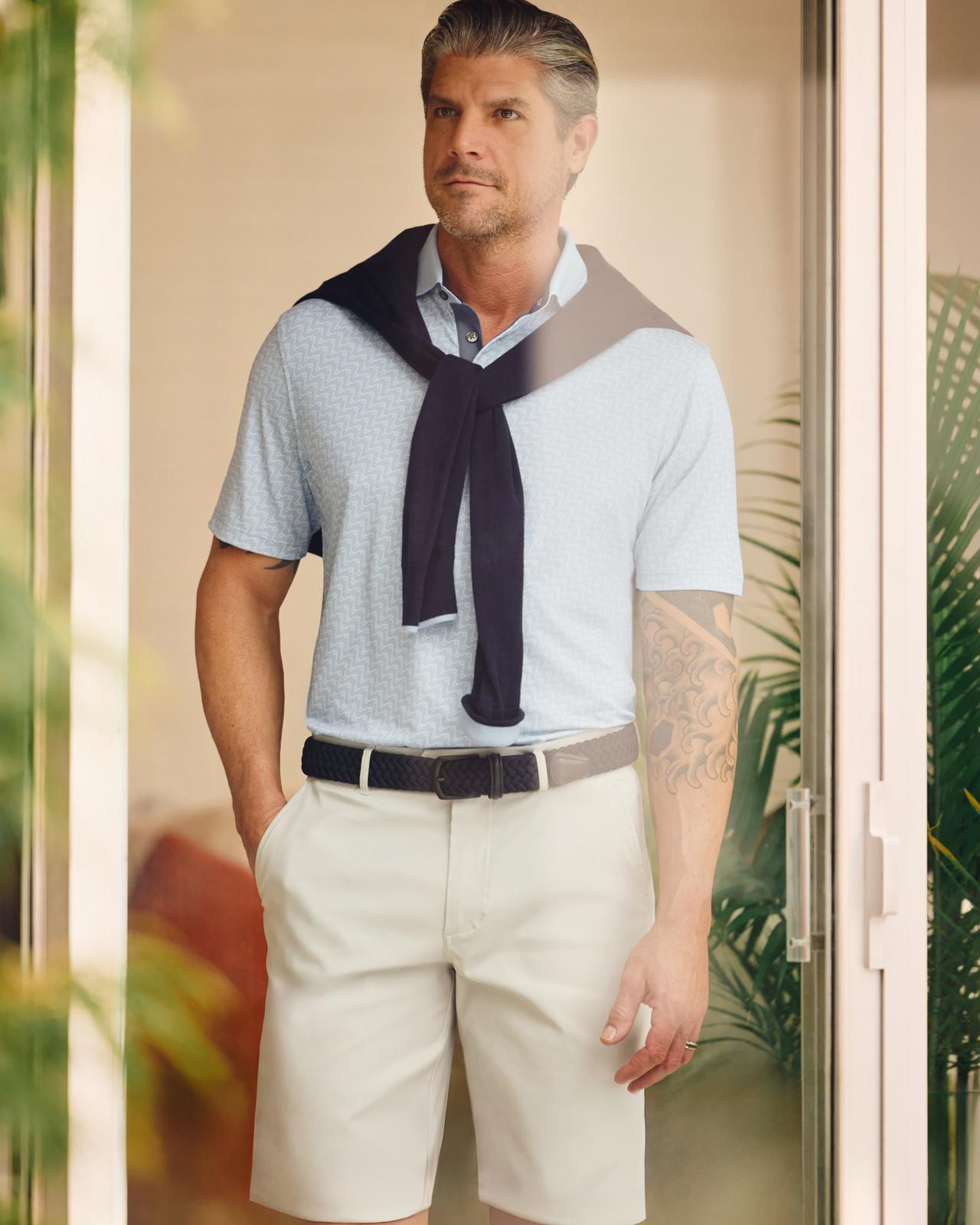 Un homme portant un t-shirt bleu clair avec un short blanc cassé