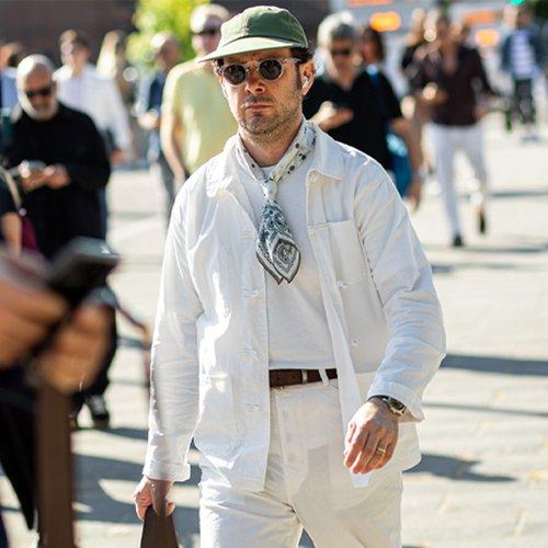male model walking in the city wearing sunglasses, hat, scarf and overshirt