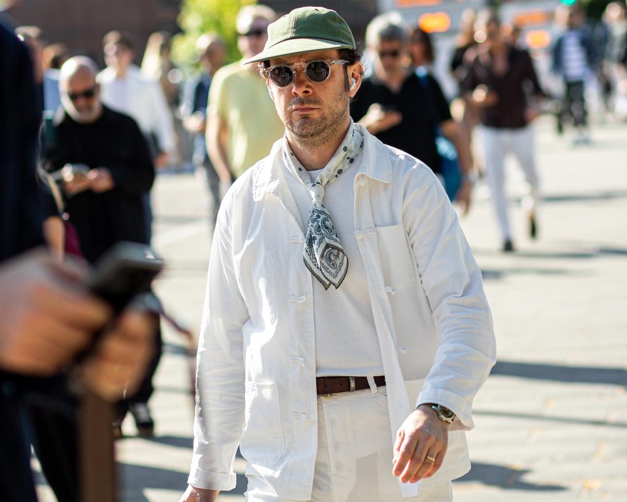 male model walking in the city wearing sunglasses, hat, scarf and overshirt