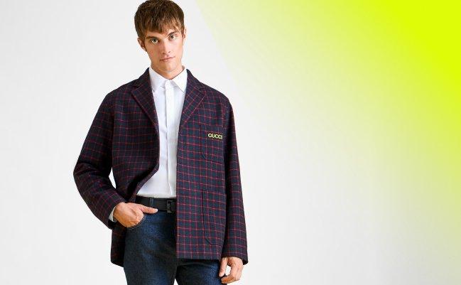  A man wearing wool checked blazer in a deep navy and red plaid pattern, paired with a white dress shirt and dark jeans