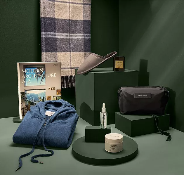 Patterned scarf, Tom Ford candle, Want Les Essentials travel bag, Blind Barber exfoliant, Patrick's night serum, Derek Rose blue sweater, Taschen coffee table book, and BOSS slippers