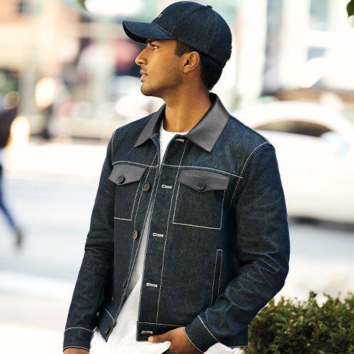 Homme portant une veste en denim foncé, une chemise blanche et une casquette noire à l’extérieur