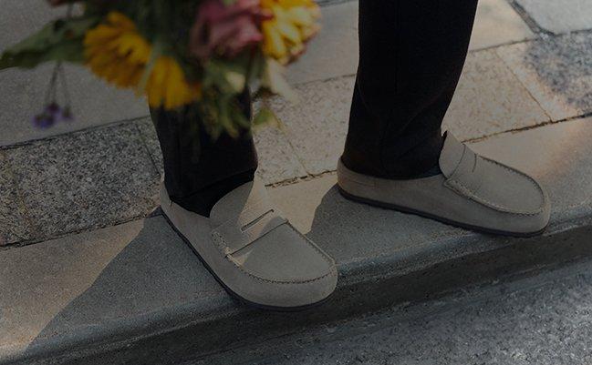 Person wearing beige loafers standing on a stone step