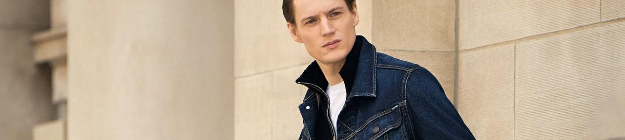 Homme portant une veste en denim superposée à un t-shirt blanc avec un jean bleu foncé