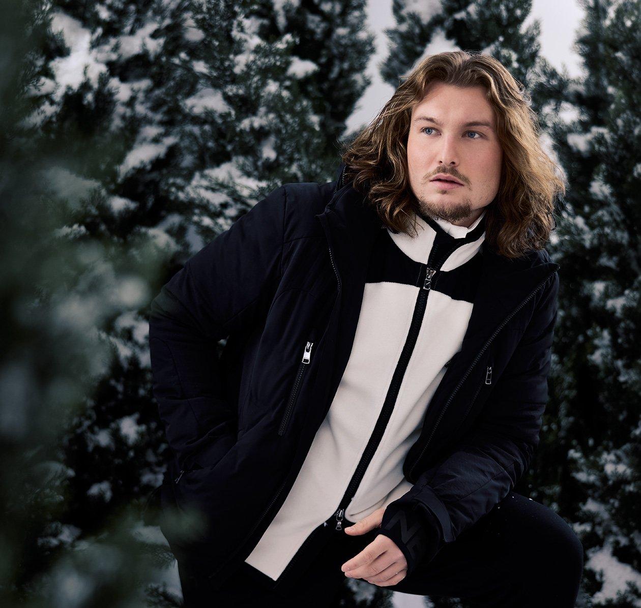 Male model outside wearing parka and lightweight jacket illustrating a ski escape