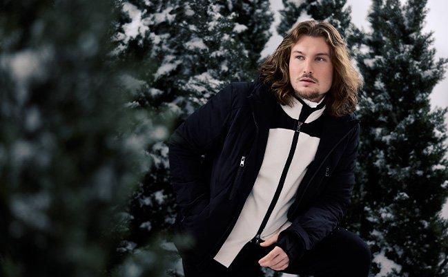 Male model outside wearing parka and lightweight jacket illustrating a ski escape