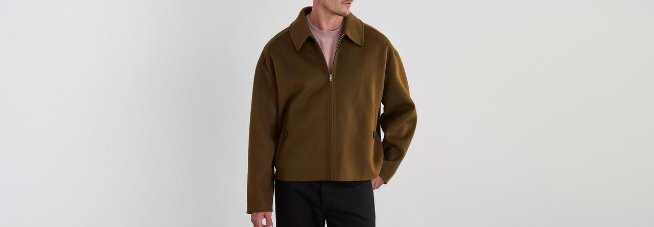 A man wearing Acne Studios brown puffer jacket with black pants 