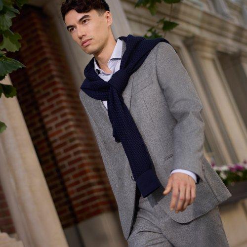 Homme portant un complet gris pâle BOSS avec un chandail bleu marine posé sur les épaules