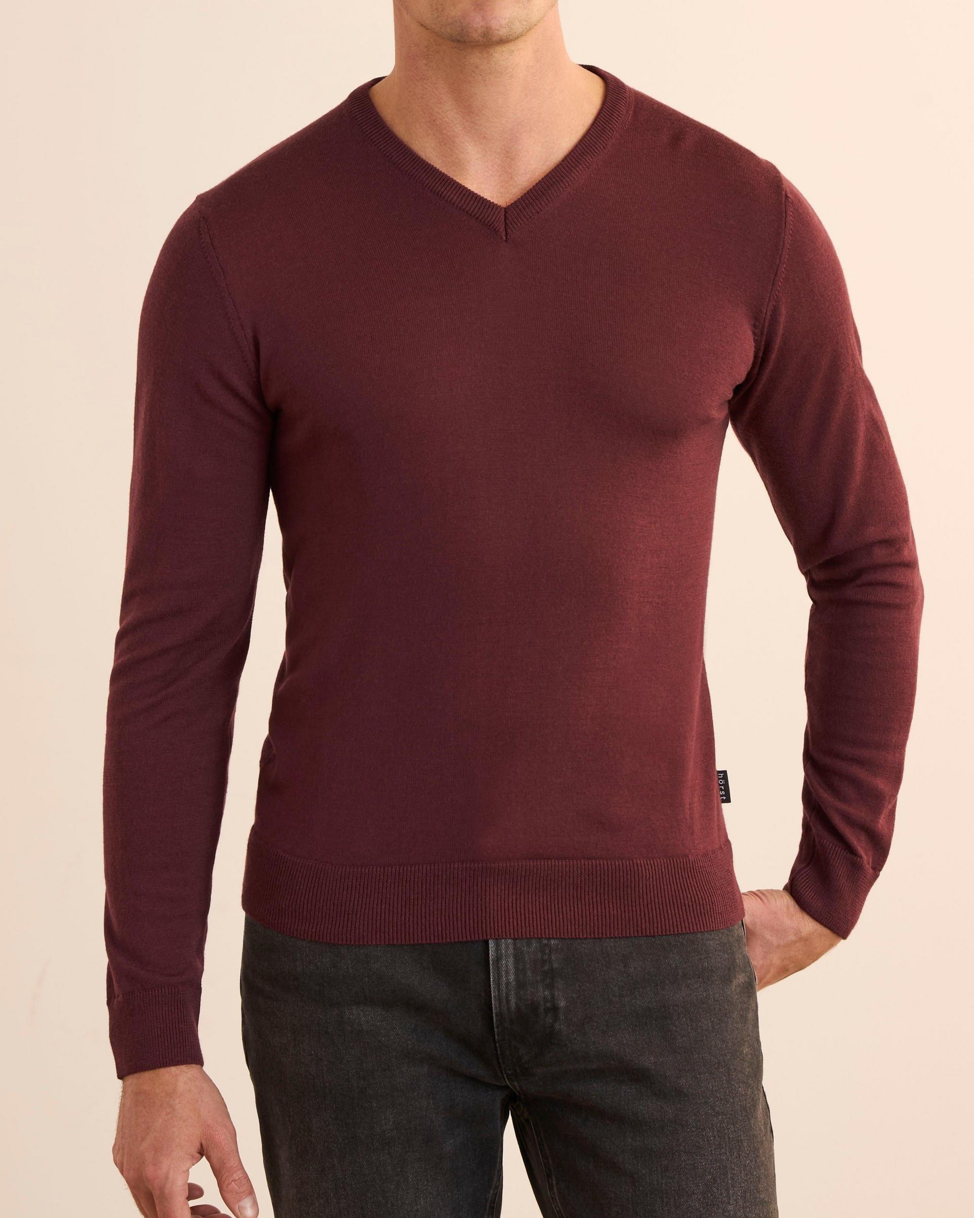 A model wearing a burgundy merino wool V-neck sweater