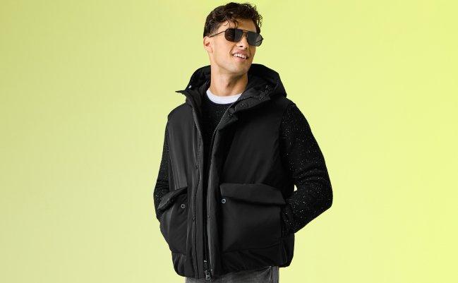A male model wearing a heavyweight winter jacket paired with an all-black casual outfit and black sunglasses