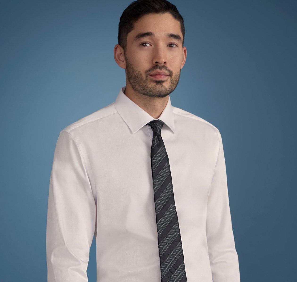 Homme vêtu d’une chemise blanche boutonnée, portée avec une cravate bleue