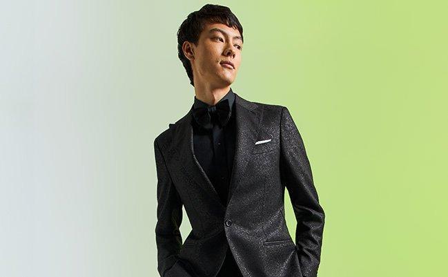 Un mannequin masculin porte un complet Harold noir texturé et ajusté, agencé à un nœud papillon noir et une chemise habillée