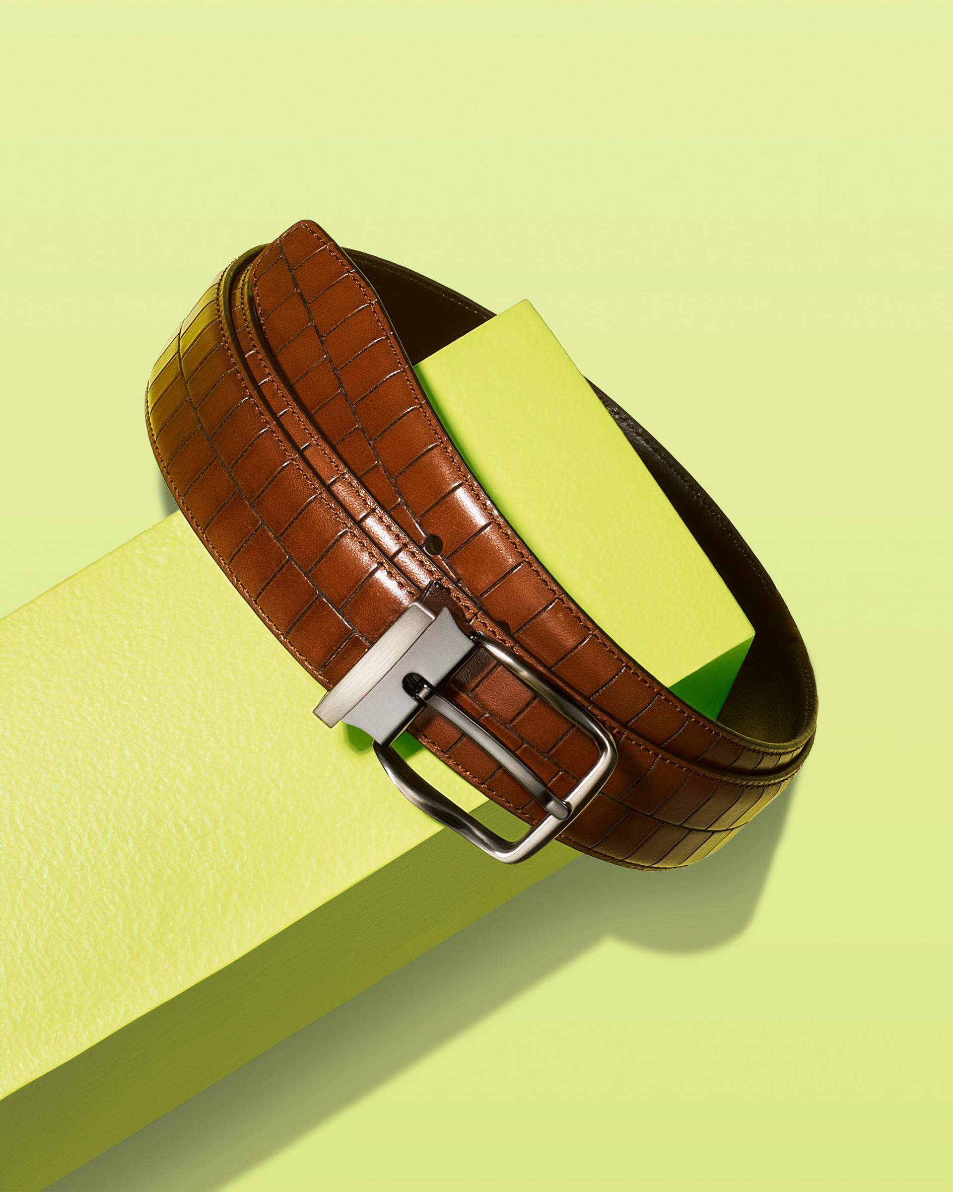Une ceinture en cuir brun présentée sur un présentoir vert lime