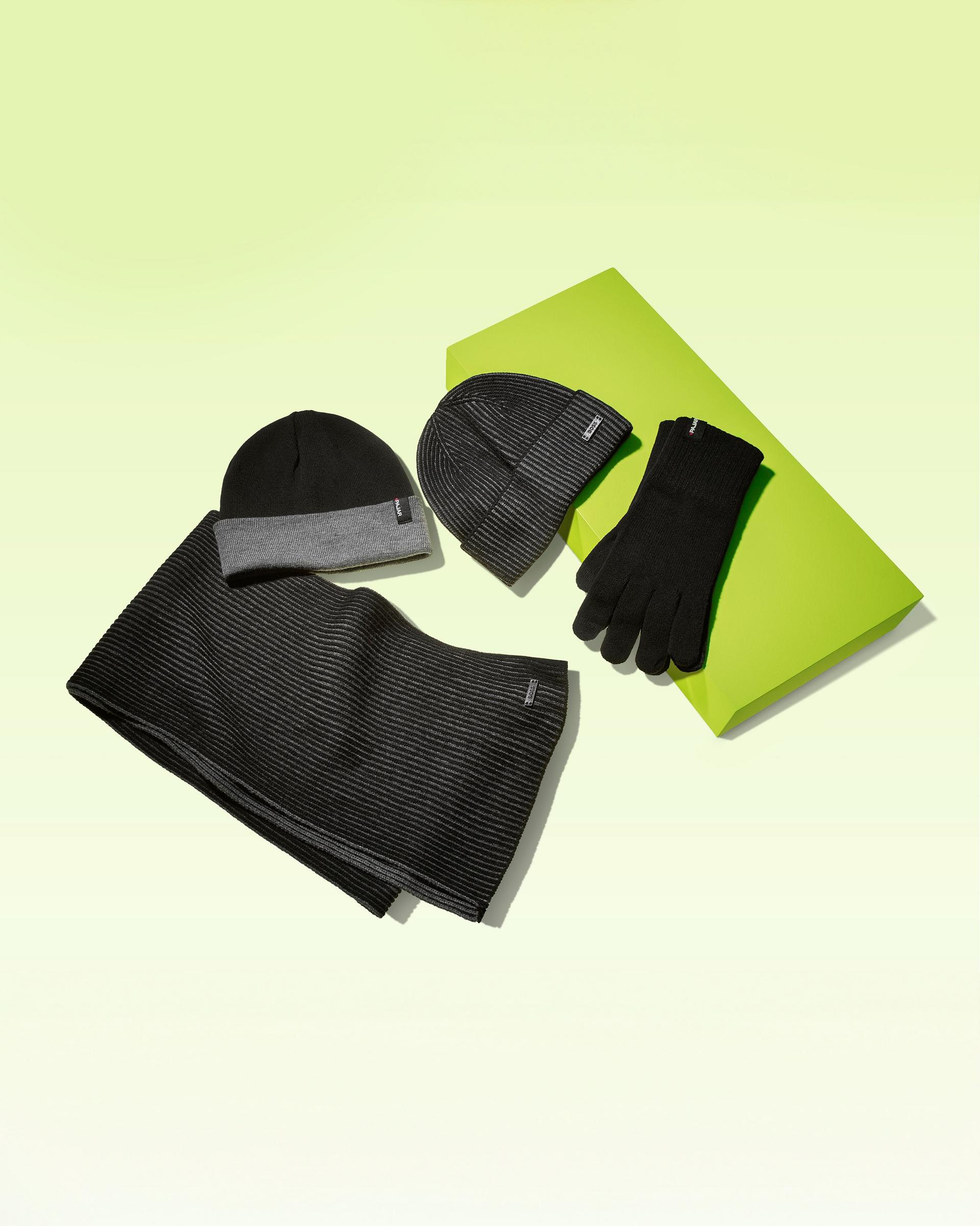 Grey and black hats, gloves and a scarf on a lime green display