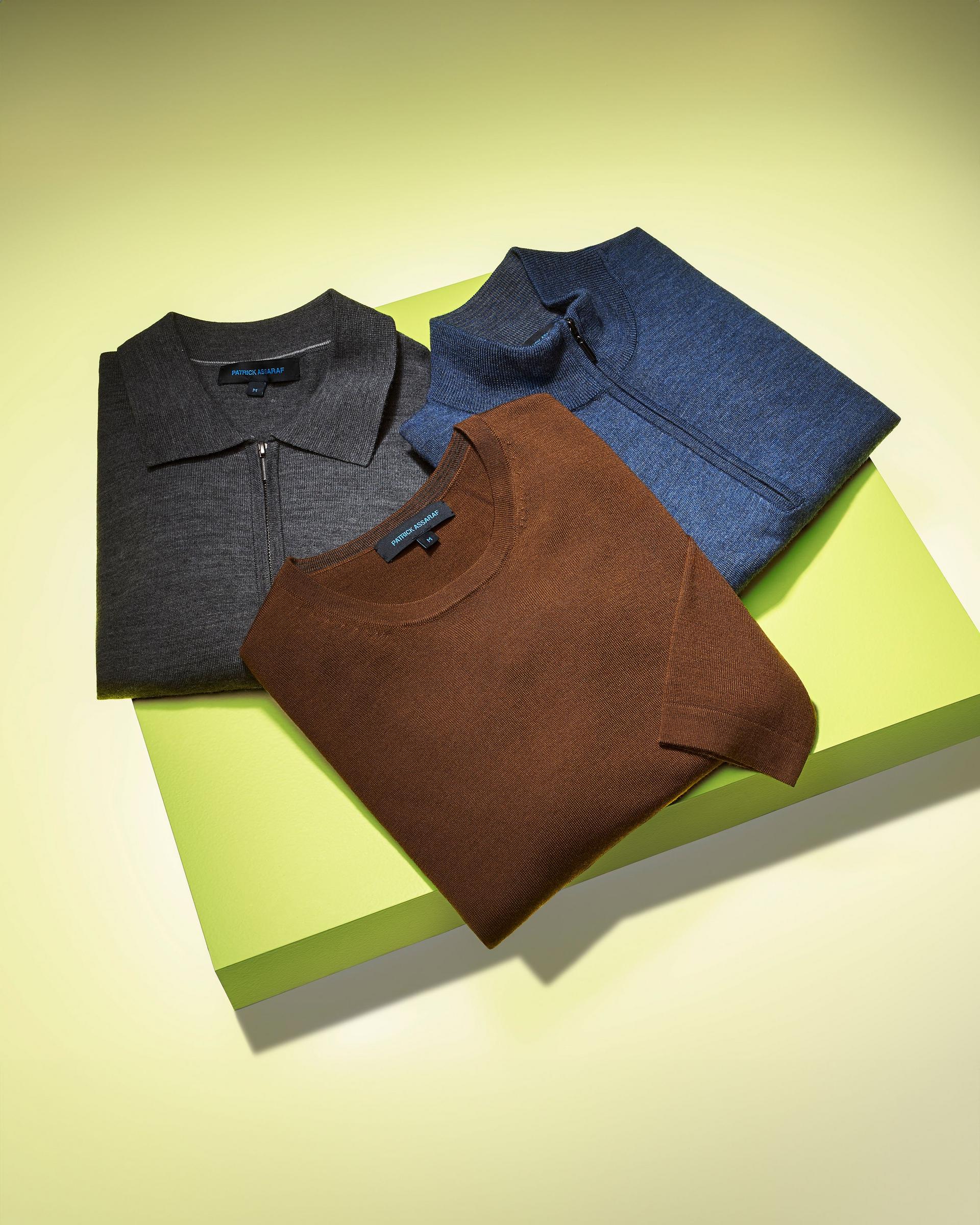 Three soft knit sweaters on a lime green display